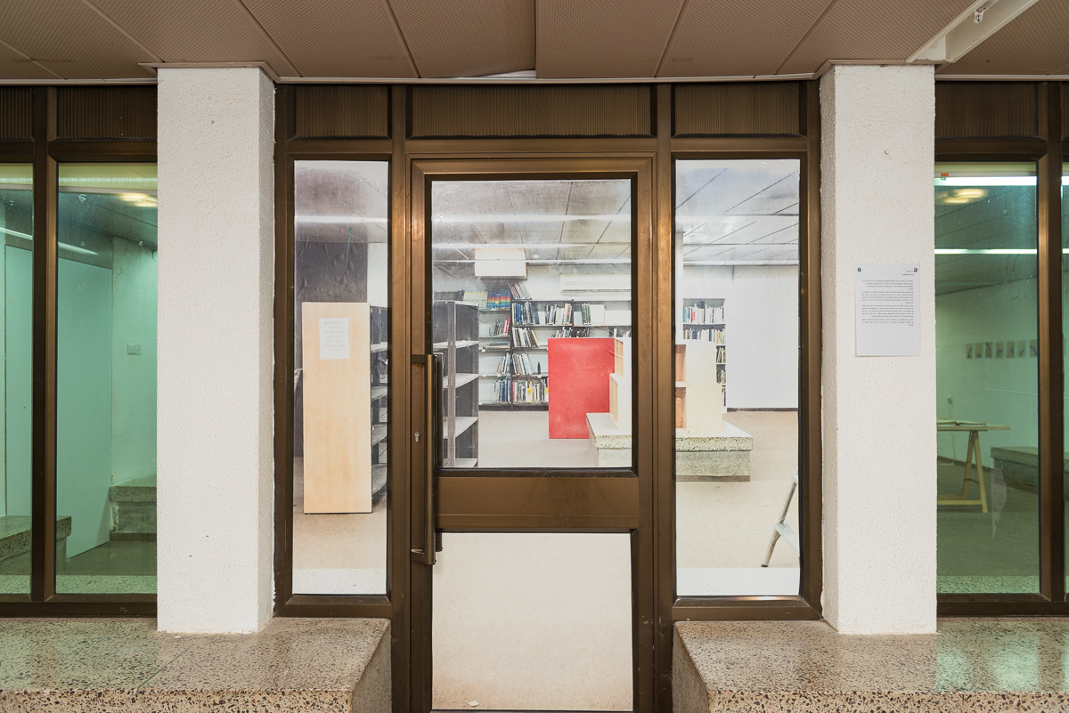 צילום של ניר דבוראי על דלת הספריה - צילום פנים החלל לפני הטיפול בו על ידי 4 אמנים שמציגים בו.